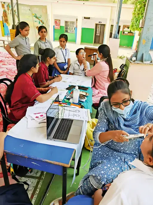 At the camp in Pilani: Dr. Mallika Adapa checks a child's teeth with the Dentyaan Cam, with the laptop on the table beside her.